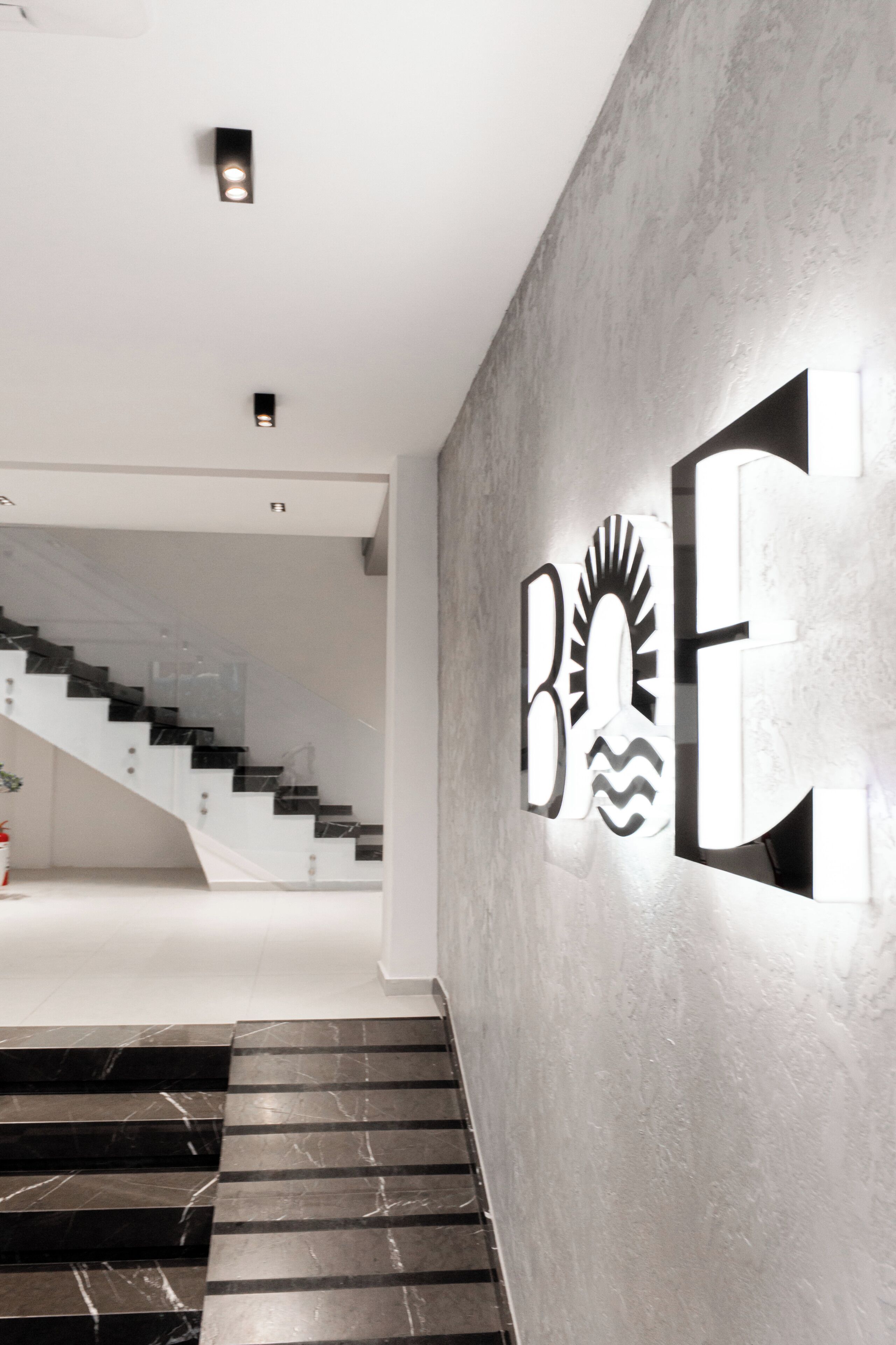 A modern interior with a staircase, a wall-mounted sign, and a ceiling light fixture.