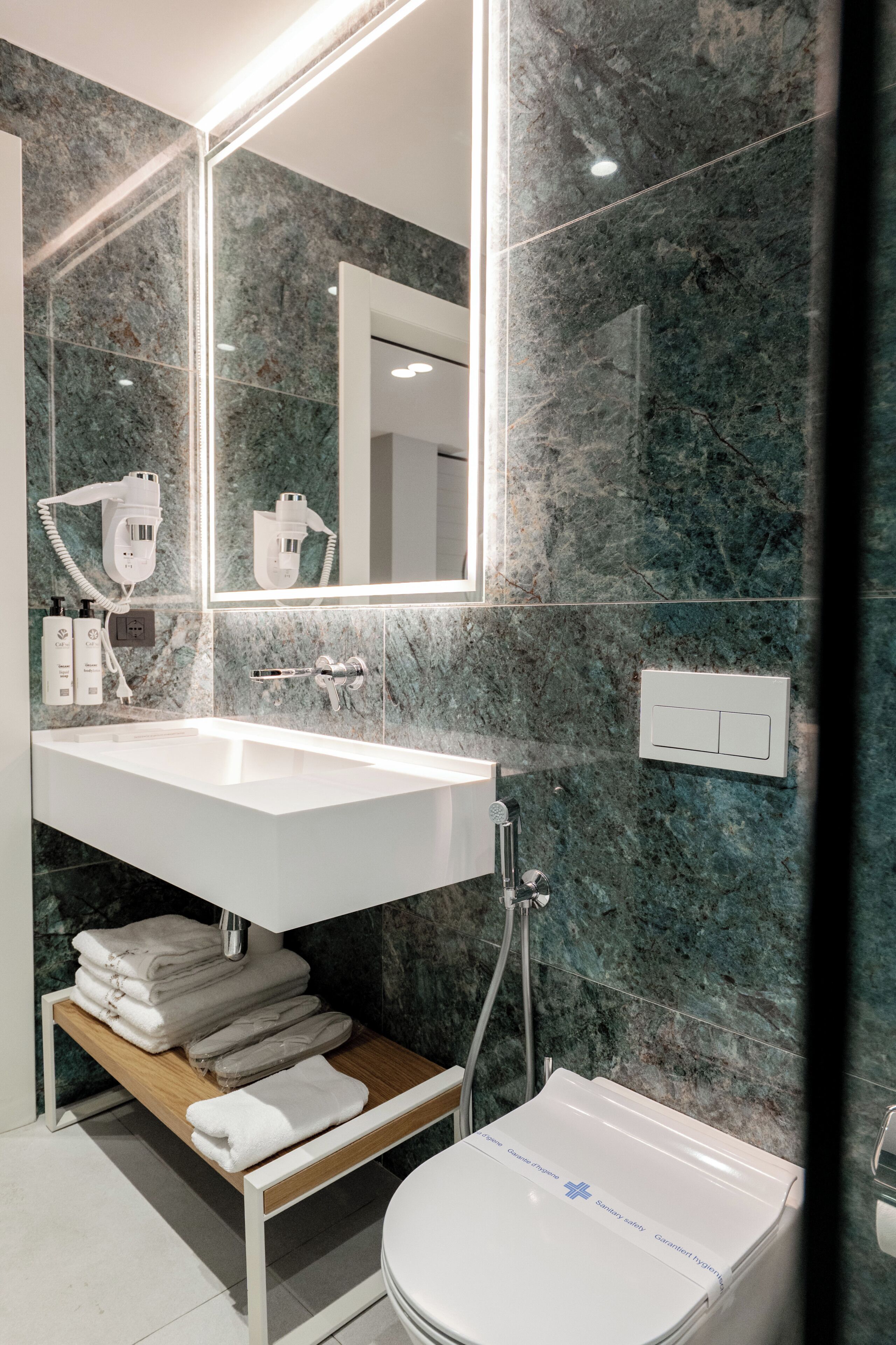 A bathroom with a white sink, a mirror, a towel rack, and a toilet.