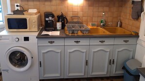 Eine kleine Küche mit Waschmaschine, Mikrowelle, Kaffeemaschine und Spüle.