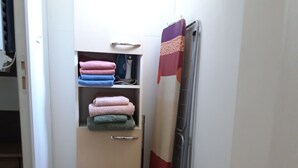 Ein kleines Zimmer mit Holzboden, einem kleinen Schrank voller gefalteter Handtücher und einer Heizung.