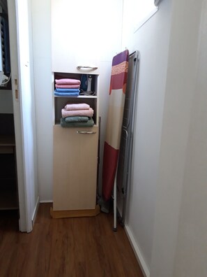 Ein kleines Zimmer mit Holzboden, einem kleinen Schrank voller gefalteter Handtücher und einer Heizung.