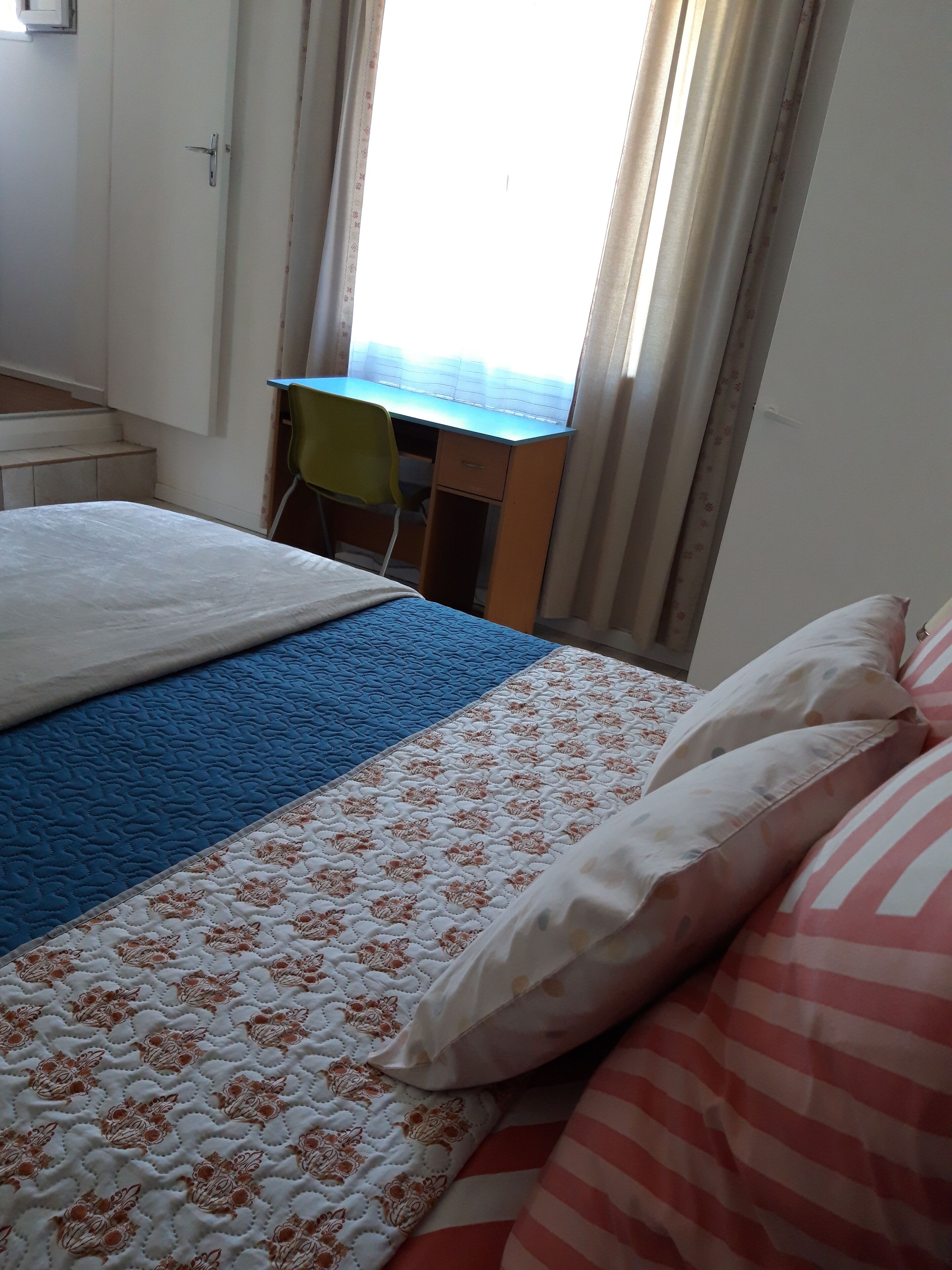 A hotel room with a bed, a desk, and a chair.