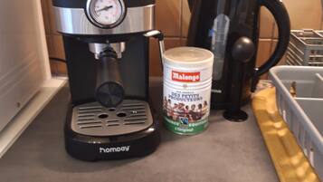 En kaffemaskine, en beholder med Malongo-kaffe og en sort kaffekande på en køkkenbordplade.