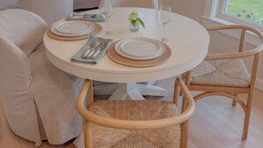 Un coin repas avec une table ronde dressée pour quatre personnes, entourée de chaises en osier.