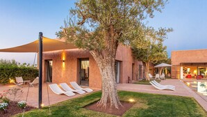 Ein moderner Außenbereich mit Lounge-Möbeln, einem Baum und einem Pool.
