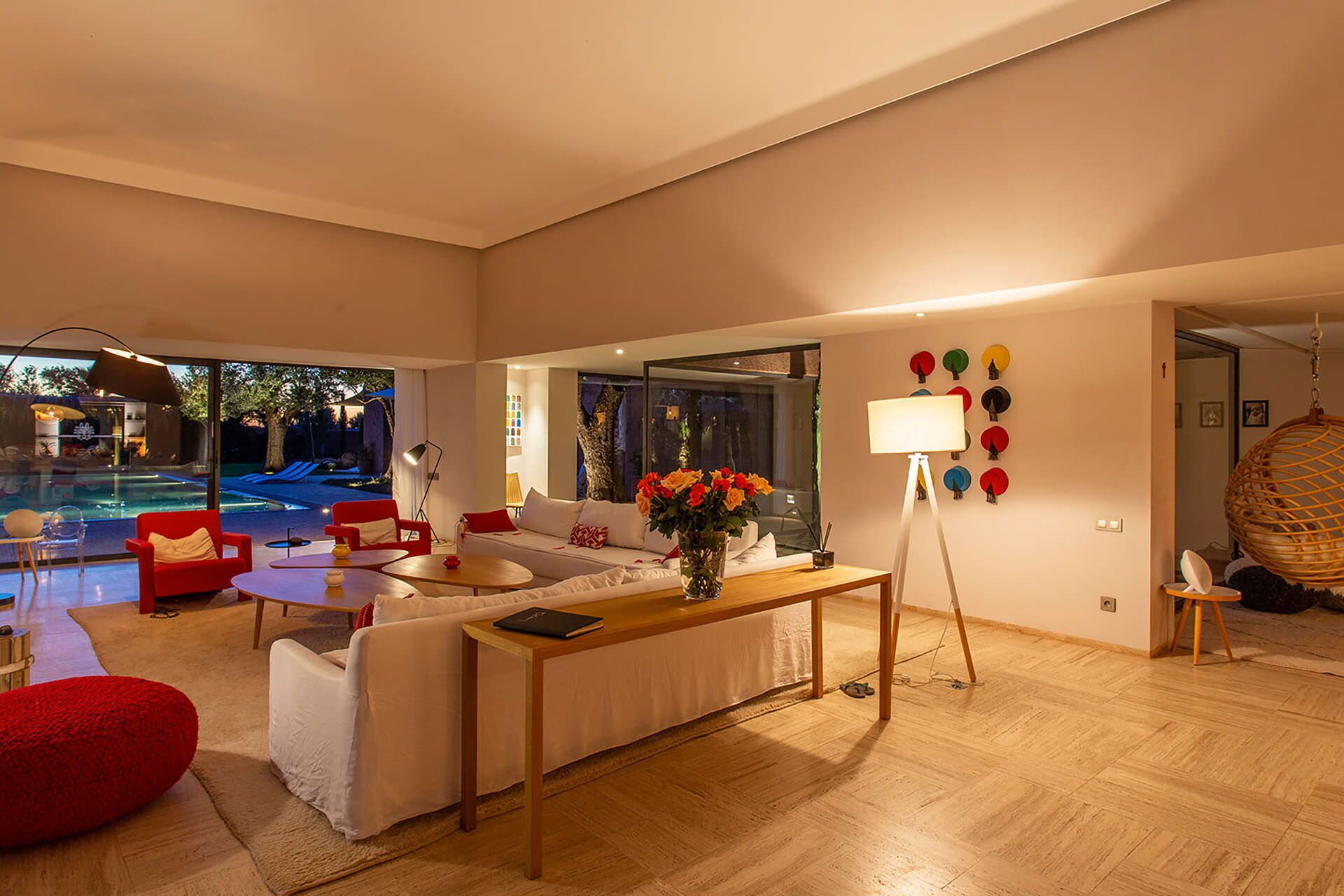 Una sala de estar moderna con vista a la piscina, un conjunto de sofás, una mesita de centro y una lámpara.