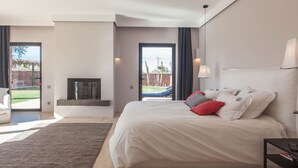 Ein modernes Schlafzimmer mit einem großen Bett, einem an der Wand montierten Fernseher und Blick auf einen Garten mit einem Pool.