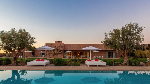 Ein modernes Resort mit Pool, Sitzgelegenheiten im Freien und einem großzügigen Haus mit Terrasse.