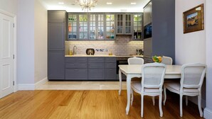 A modern kitchen with grey cabinets, a white countertop, and a dining area with white chairs. - The Westminster Courtyard Apartment, by Veeve (London)