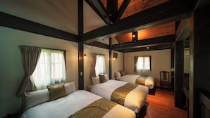 Habitación de hotel con tres camas, vigas de madera y una pequeña mesa.