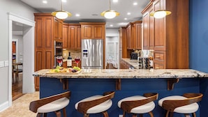 A modern kitchen with wooden cabinets, stainless steel appliances, and a granite countertop. - Asheville Mansion: Spa, Games, Sleeps 28 (Fletcher)