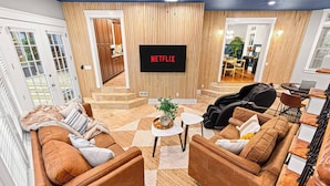 A modern living room with a large flat-screen TV, a sofa set, a massage chair, and a coffee table. - Asheville Mansion: Spa, Games, Sleeps 28 (Fletcher)