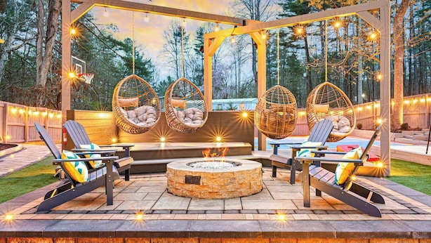 An outdoor patio with wicker chairs, a fire pit, and string lights. - Asheville Mansion: Spa, Games, Sleeps 28 (Fletcher)