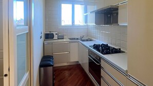 A compact kitchen with white cabinets, a stainless steel sink, and a microwave.