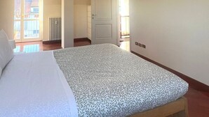 A bedroom with a bed, a radiator, and a view of the outside.