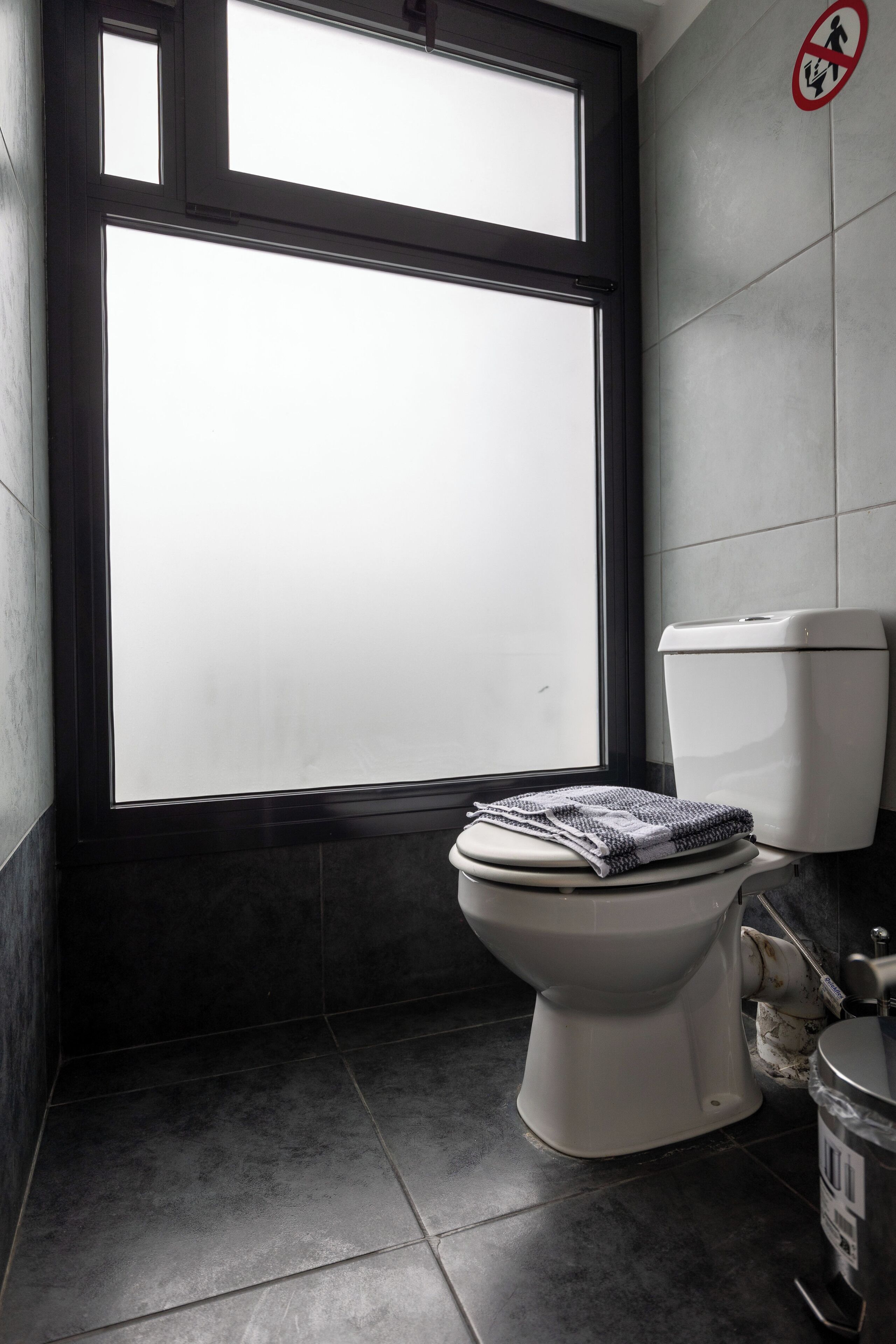 Un baño con inodoro, una ventana y un letrero de 'prohibido el acceso'.