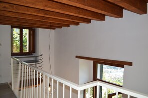 Eine Treppe mit weißen Geländern und Holzbalken, die zu einem Balkon mit Blick auf eine Stadtlandschaft führt.
