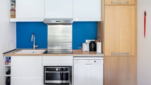 Ett kompakt kök med vita skåp, en fläktkåpa i rostfritt stål, en diskmaskin från Bosch och en mikrovågsugn.