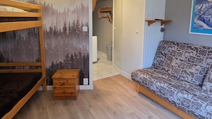 A room with a bunk bed, a patterned sofa, a forest mural, and a framed picture on the wall. - Renovated studio in Avoriaz center, perfect for 4 guests (Avoriaz)