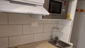 A kitchen with a stainless steel sink, a microwave, and a range hood above the stove. - Renovated studio in Avoriaz center, perfect for 4 guests (Avoriaz)