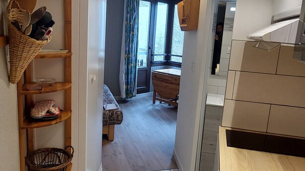 A modern kitchen with a wooden countertop and cabinets, a dining area with a bench, and a view through a window with curtains. - Renovated studio in Avoriaz center, perfect for 4 guests (Avoriaz)