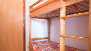 A bunk bed with a colorful quilt, a wooden door, and a tiled floor. - Cozy apartment in Aussois for 3/4 guests, near shuttles (Aussois)