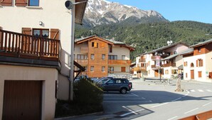 A mountain-view hotel with multiple balconies, a parking area, and a clear view of snow-capped mountains. - Cozy apartment in Aussois for 3/4 guests, near shuttles (Aussois)