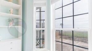 A room with a large window, a white bench, and shelves with decorative items. - Sandy Shores - Babe's Beach / Welcomes 8 (Galveston)