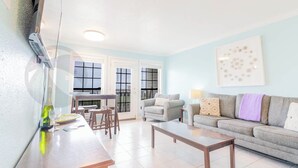 A living room with a sofa, a coffee table, and a dining area with chairs and a table. - Sandy Shores - Babe's Beach / Welcomes 8 (Galveston)