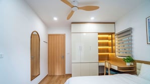 Un dormitorio con cama, escritorio, armario y ventilador de techo.