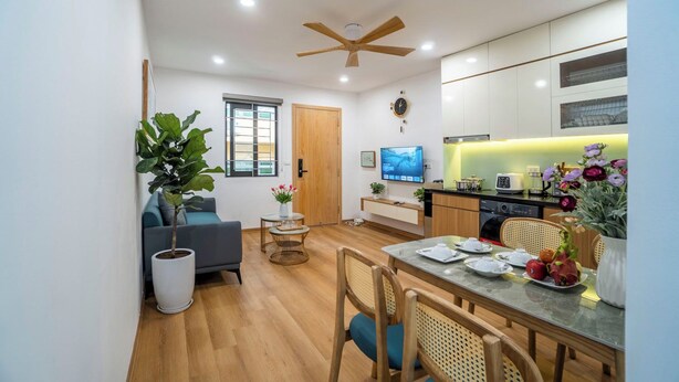 Un espacio habitable compacto con comedor, kitchenette y zona de estar con sofá y mesa de centro.