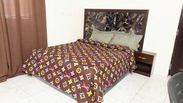 A bed with a patterned bedspread, a headboard with a marble-like design, and a nightstand with a drawer.