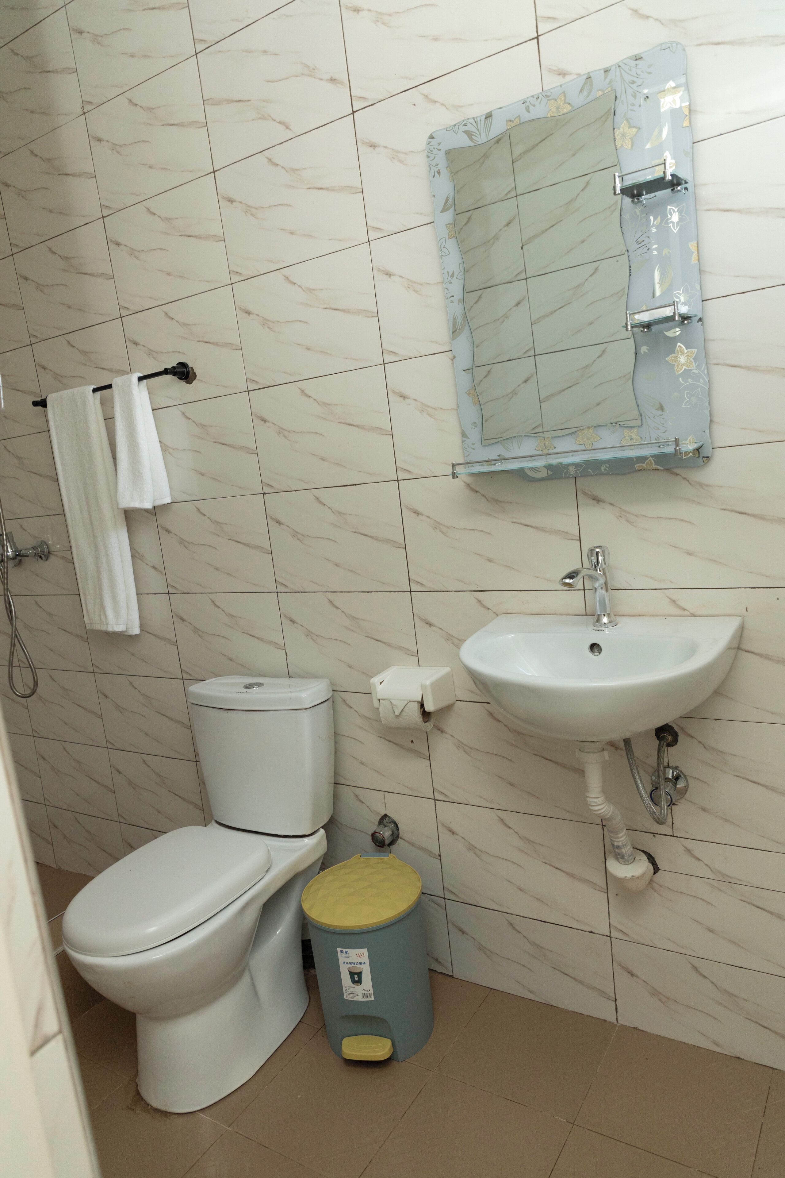 A bathroom with a toilet, sink, and a trash bin.