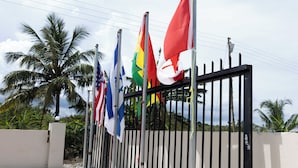 A gated area with multiple flags, including the American flag, a flag with a red, yellow, and green design, and a flag with a white and red design.