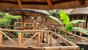Una terraza de madera con techos de paja y una valla de madera.
