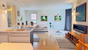 A modern living room with a sofa, a coffee table, a TV, and artwork on the walls. - DiamondVilla, 4 bedroom Apartment, garden & spa (Hlavní mesto Praha)