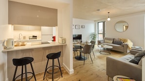 Un apartamento moderno con cocina, comedor y sala de estar. Incluye un taburete, una mesa de comedor y un sofá.