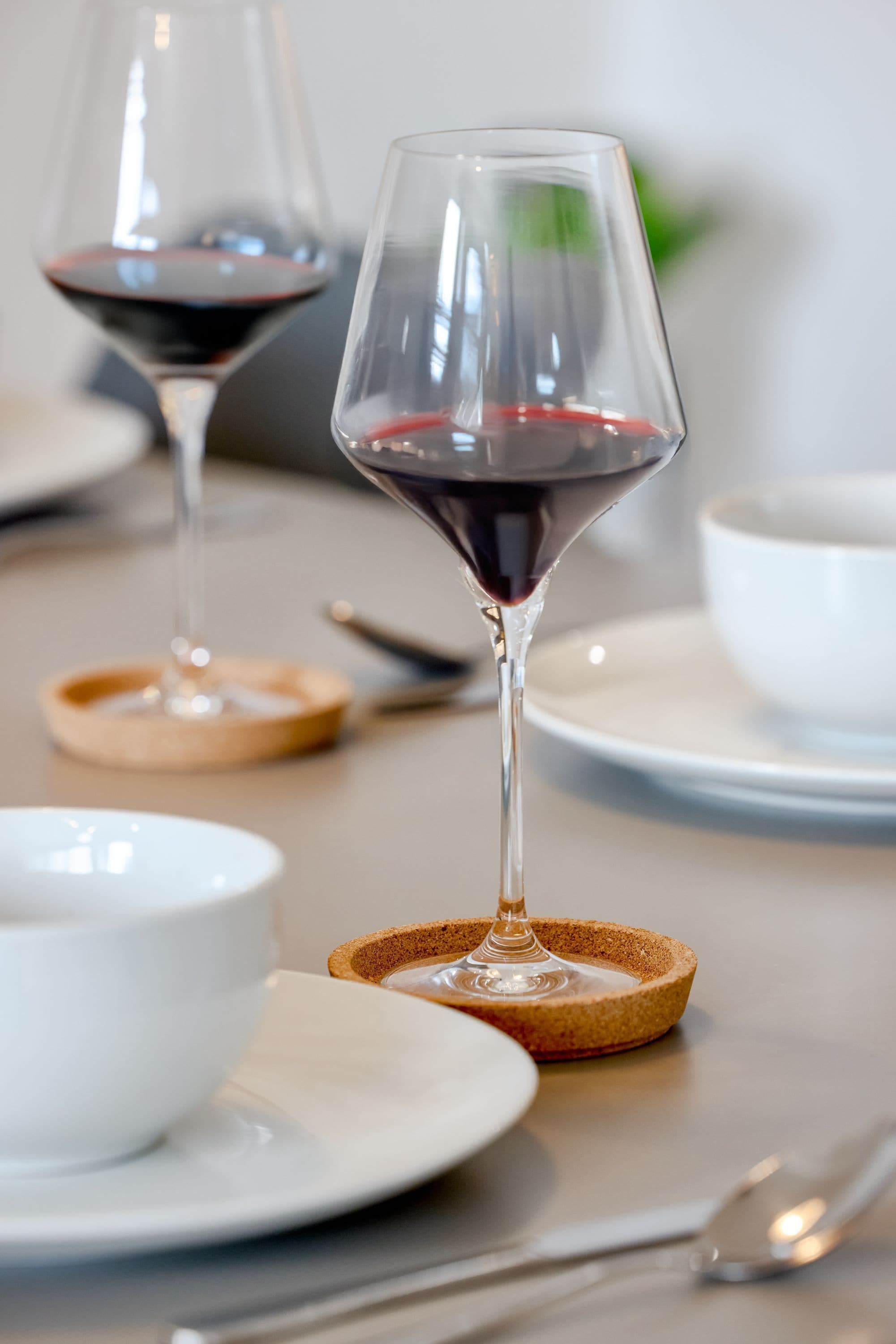 Uma mesa com duas taças de vinho, uma tigela branca e uma colher.