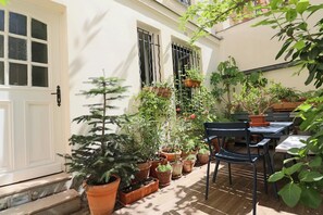 A patio area with potted plants, a table, and chairs. - La Rochefoulcaud Citycosy (Paris)
