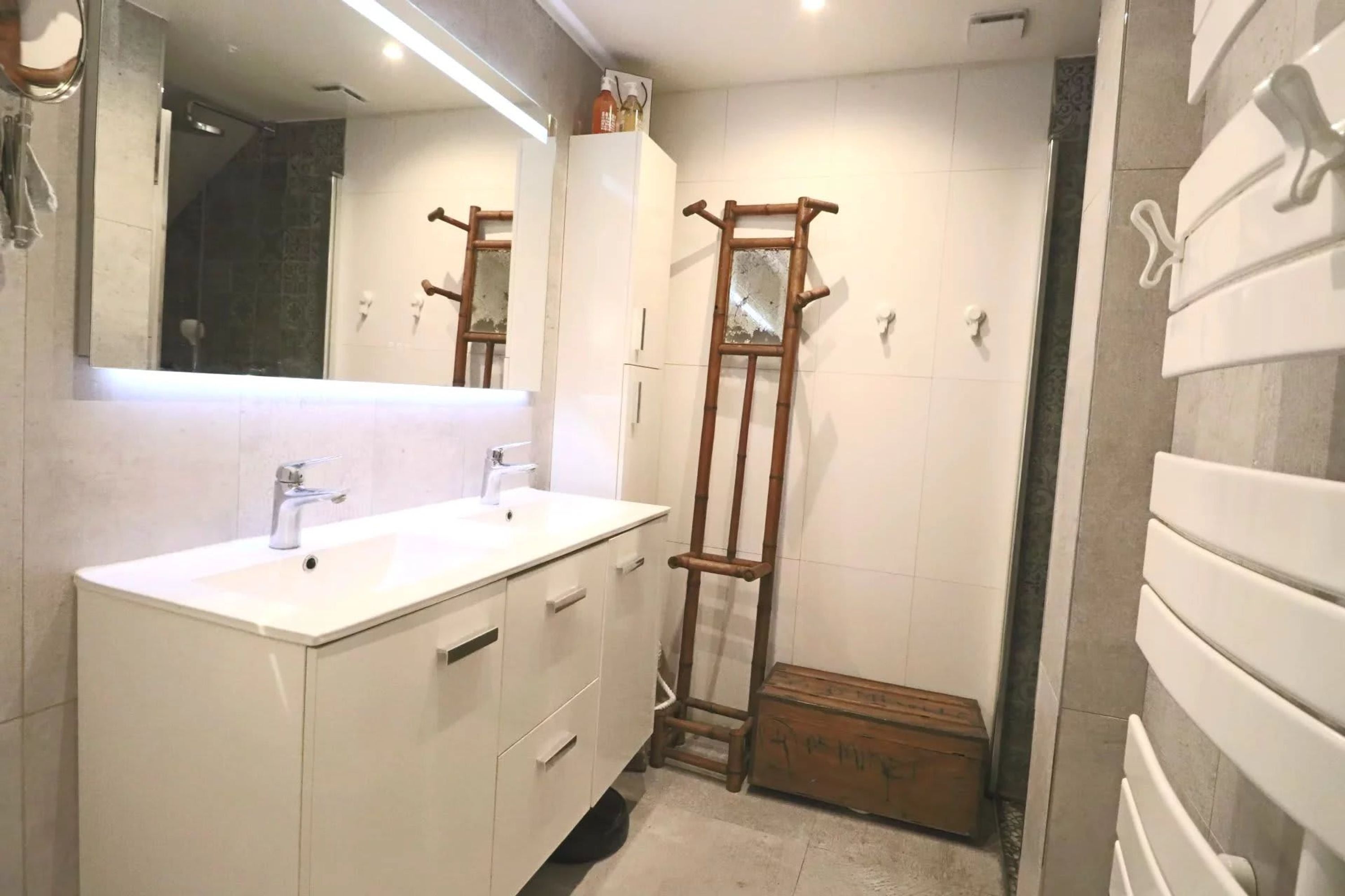 A bathroom with two sinks, a mirror, a shower, and a wooden ladder.