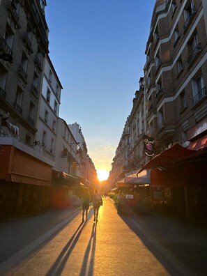 Una strada fiancheggiata da edifici, con un tramonto sullo sfondo.