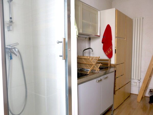 A bathroom with a shower, a sink, and a drying rack. - Studio Camille Desmoulins Citycosy (Paris)