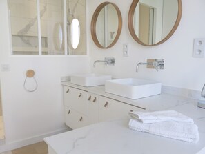 A modern bathroom with two sinks, a large mirror, and a towel rack.