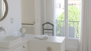 Une salle de bain minimaliste avec un meuble-lavabo blanc, un miroir rond et une petite poubelle.
