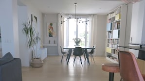 Un salon moderne comprenant un coin repas, une bibliothèque et une plante en pot.