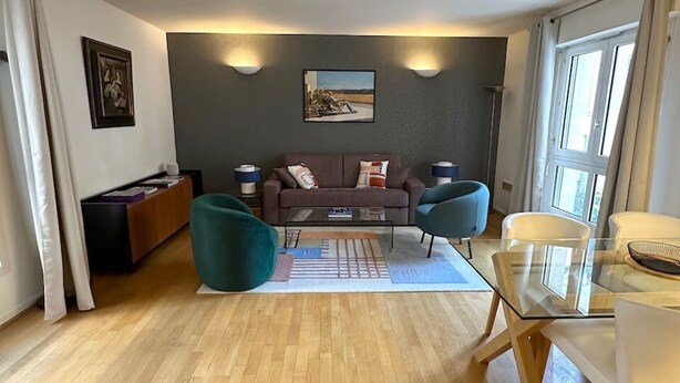 A modern living room with a sofa, two armchairs, a glass coffee table, and a dining table. - Appartement Grand Veneur Citycosy (Paris)