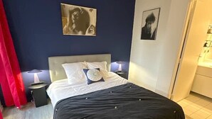 A bedroom with a bed, two bedside tables, a nightstand, and a red curtain. - Appartement Grand Veneur Citycosy (Paris)