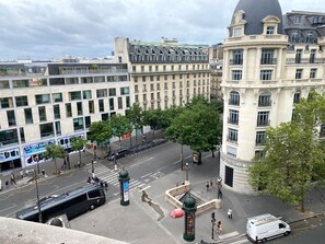 A city intersection with modern buildings, a tram, and pedestrians. - Appartement Opera Chauchat Citycosy (Paris)