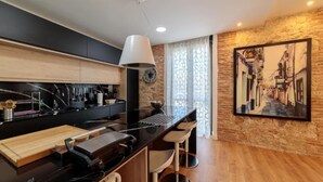 Una cucina moderna con un piano di lavoro nero, sgabelli da bar in legno e un grande quadro raffigurante una scena di strada.