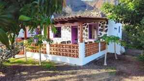 A small, rustic house with a stone facade, a wooden porch, and a purple door. - Los Cerrajones: spectacular views from the cliff (Agulo)